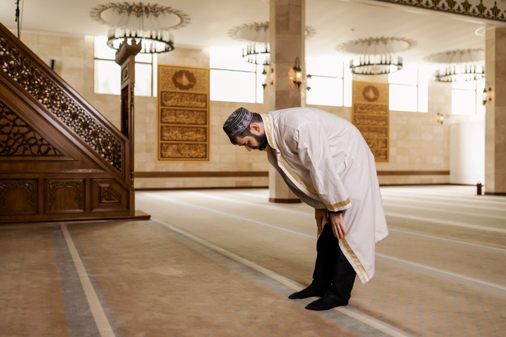A man in traditional attire praying inside a mosque, capturing spiritual devotion and Islamic culture.